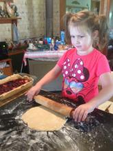 Photo of a blind girl rolling out pie crust.
